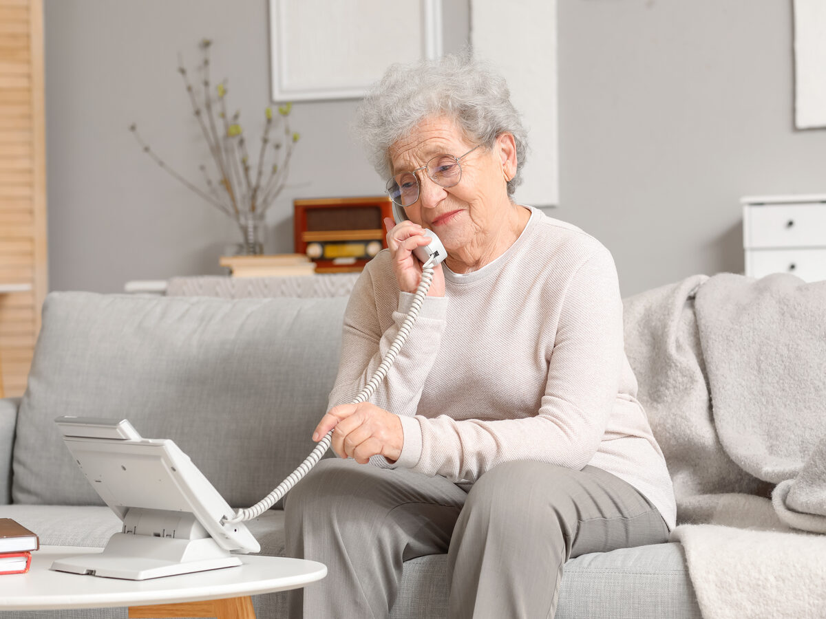 Elderly woman on the phone at home using an AI voice concierge service