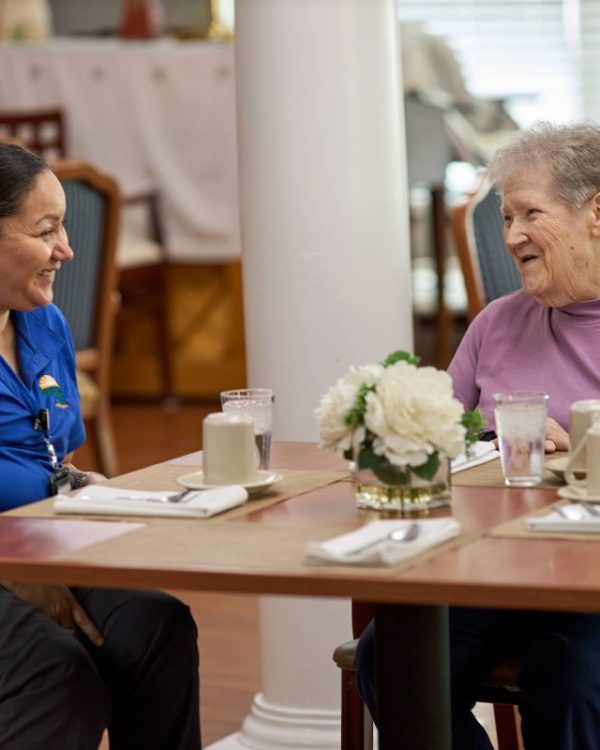 Senior living staff member enjoying coffee with a resident, showing the warm community atmosphere